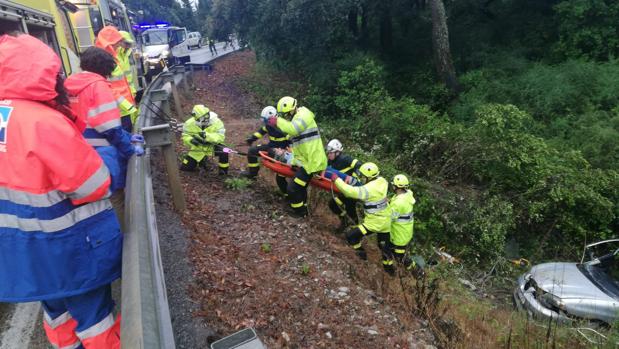 Los bomberos trasladan al herido a la ambulancia por el terraplén