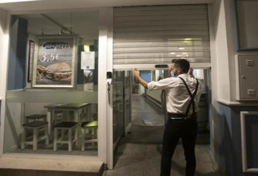 Un camarero cierra las persianas de un bar de Sevilla