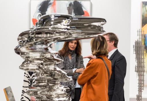 Tres personas conversan ante una pieza de Tony Cragg