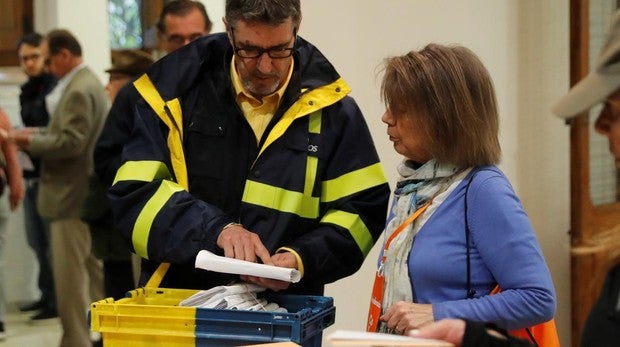 Un funcionario de correos hace entrega a la presidenta de una mesa del colegio electoral del Colegio Nuestra Señora del Pilar votos emitidos por correo
