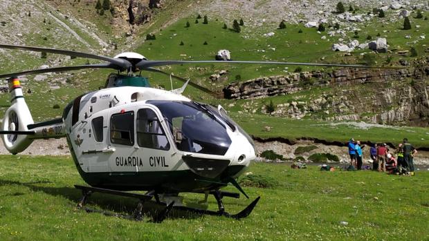 Helicóptero en el que fue evacuado el senderista. Al fondo, mientras era atendido en el lugar donde tuvo el encontronazo con las vacas de montaña, habitualmente pacíficas