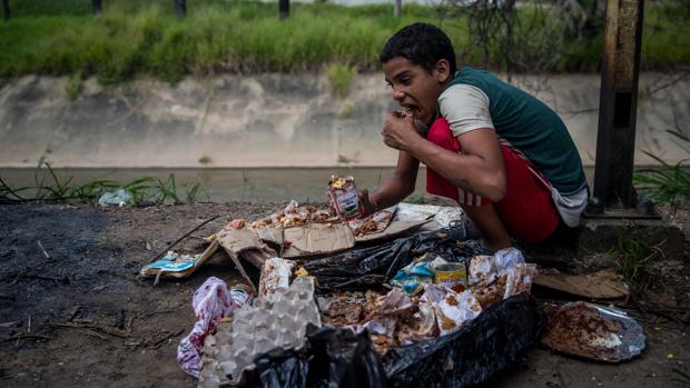 Un niño come de los restos de la basura en Caracas