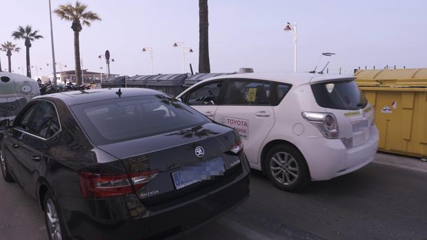 Un taxi circula junto a un Uber estacionado en el Paseo Marítimo en el estreno de la compañía en Cádiz.