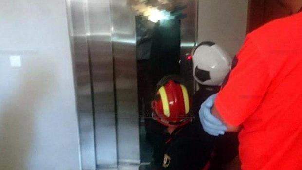 Los bomberos, en el momento en el que rescatan a la persona que cayó con el ascensor
